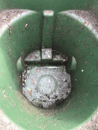A top-down view of an empty green trash bin, its worn plastic stained with dirt and scattered dried leaves—signs that it could benefit from a professional trash can cleaning service. The inner surface shows evidence of frequent use. A top-down view of an empty green trash bin, its worn plastic stained with dirt and scattered dried leaves—signs that it could benefit from a professional trash can cleaning service. The inner surface shows evidence of frequent use.